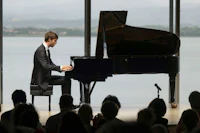 a man in a suit playing a piano in front of an audience