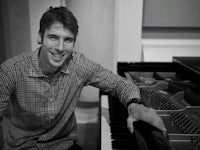 a man smiling at a piano in a recording studio